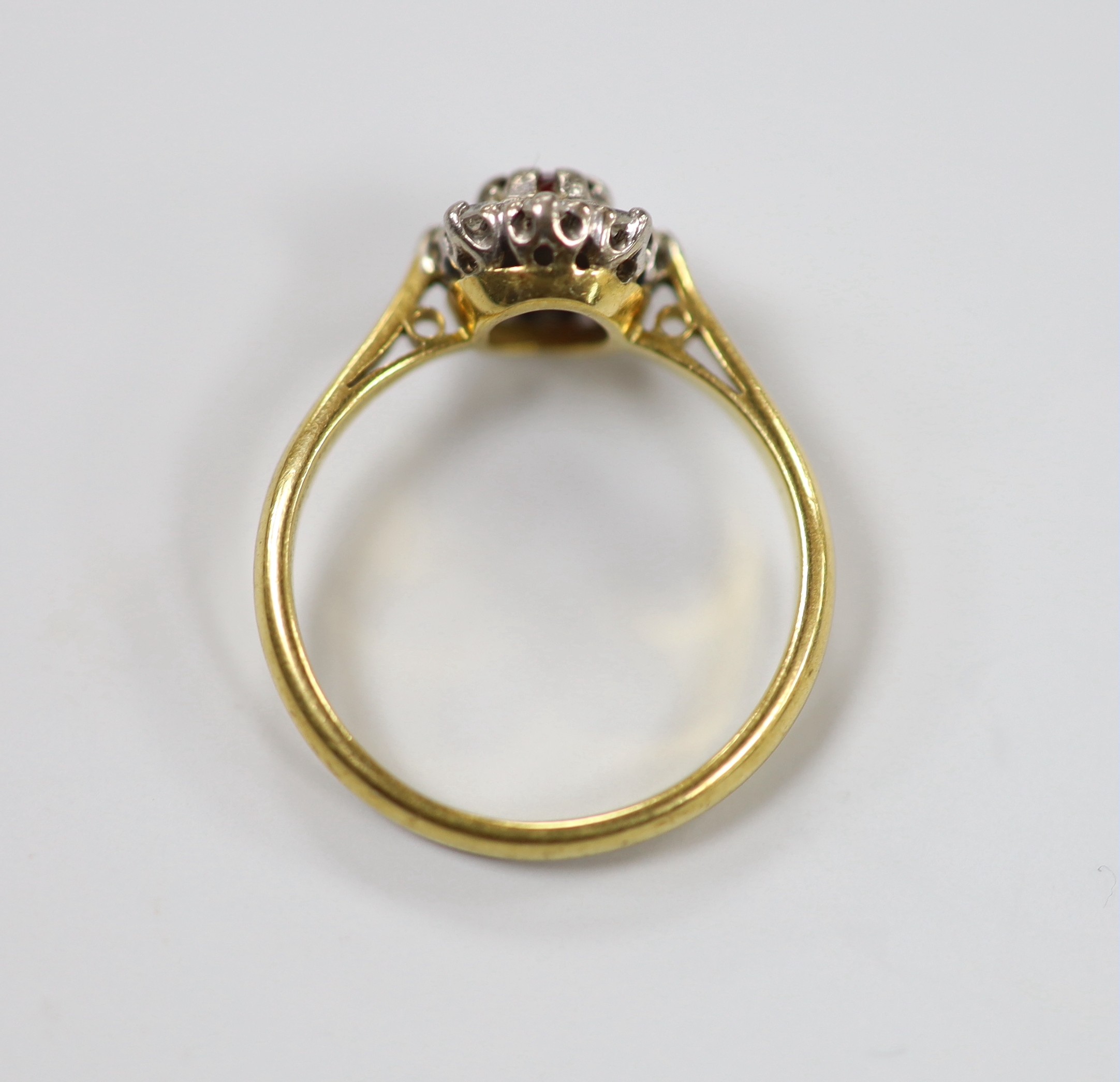 A modern 18ct gold, garnet? and diamond set oval cluster ring, size M, gross weight 3.2 grams.